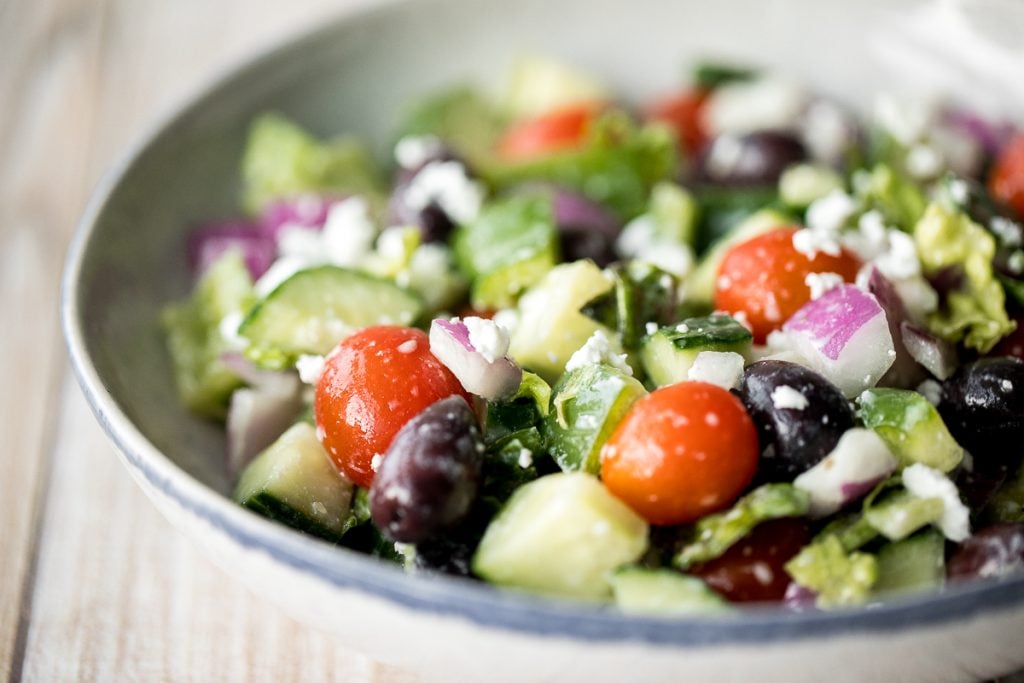 The perfect Greek salad with fresh tomatoes, cucumbers, red onions, green peppers, romaine lettuce, olives and feta cheese tossed in a lemon vinaigrette. | aheadofthyme.com