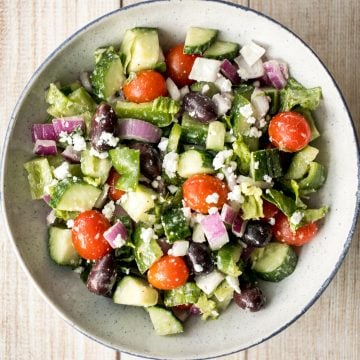 The perfect Greek salad with fresh tomatoes, cucumbers, red onions, green peppers, romaine lettuce, olives and feta cheese tossed in a lemon vinaigrette. | aheadofthyme.com