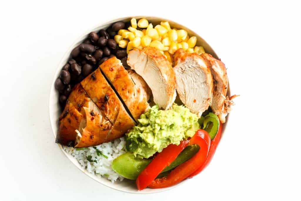 It's time for a fiesta with chipotle chicken burrito bowls served with lime cilantro rice, sautéed bell peppers, corn, black beans and guacamole. | aheadofthyme.com