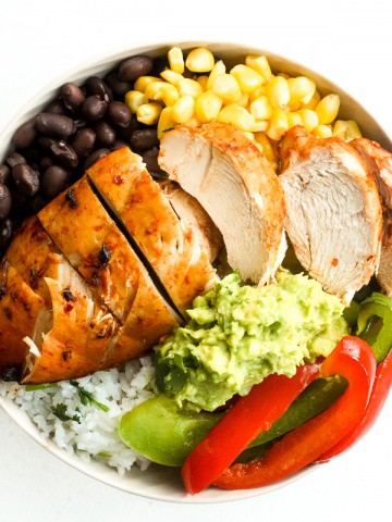 It's time for a fiesta with chipotle chicken burrito bowls served with lime cilantro rice, sautéed bell peppers, corn, black beans and guacamole. | aheadofthyme.com