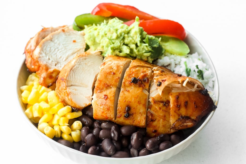 It's time for a fiesta with chipotle chicken burrito bowls served with lime cilantro rice, sautéed bell peppers, corn, black beans and guacamole. | aheadofthyme.com