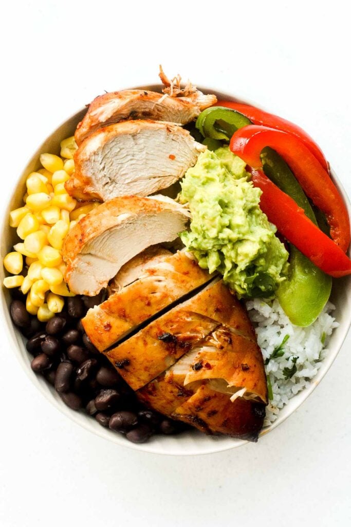 It's time for a fiesta with chipotle chicken burrito bowls served with lime cilantro rice, sautéed bell peppers, corn, black beans and guacamole. | aheadofthyme.com