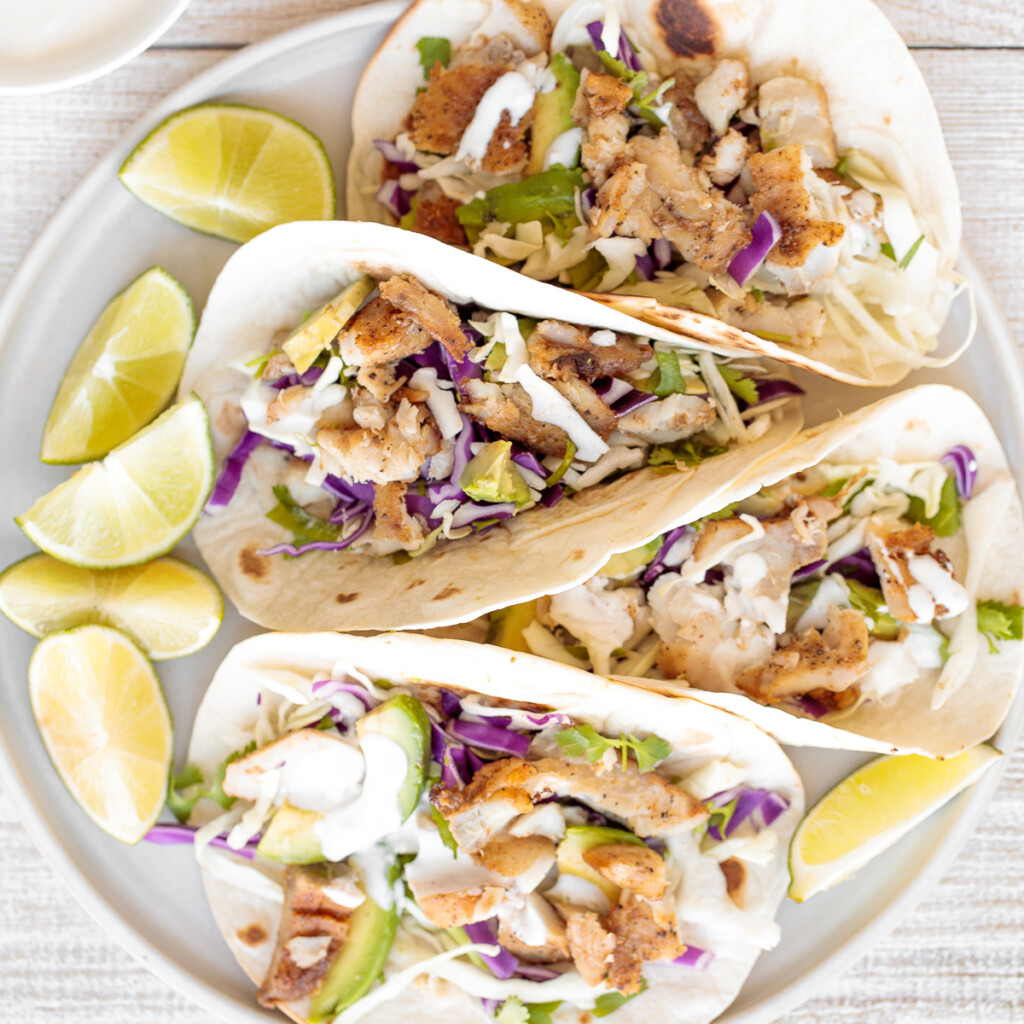 Flavourful, easy fish tacos with lime crema is made with seasoned white fish, cabbage slaw, and lime sauce. It takes less than 25 minutes to prep and serve. | aheadofthyme.com