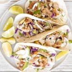 Flavourful, easy fish tacos with lime crema is made with seasoned white fish, cabbage slaw, and lime sauce. It takes less than 25 minutes to prep and serve. | aheadofthyme.com