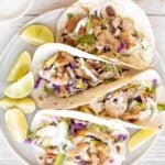 Flavourful, easy fish tacos with lime crema is made with seasoned white fish, cabbage slaw, and lime sauce. It takes less than 25 minutes to prep and serve. | aheadofthyme.com