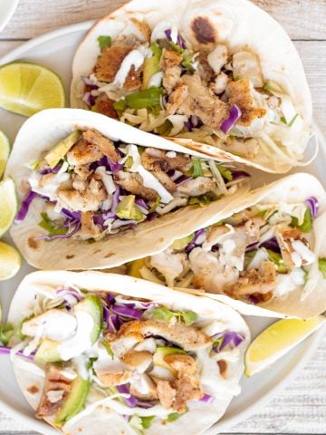 Flavourful, easy fish tacos with lime crema is made with seasoned white fish, cabbage slaw, and lime sauce. It takes less than 25 minutes to prep and serve. | aheadofthyme.com