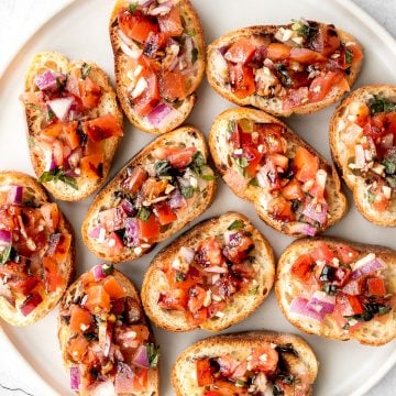 Tomato bruschetta with balsamic glaze is an easy Italian appetizer topped with tomatoes, onions, garlic, basil and olive oil. Delicious, fresh and simple. | aheadofthyme.com