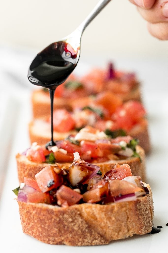 Tomato bruschetta with balsamic glaze is an easy Italian appetizer topped with tomatoes, onions, garlic, basil and olive oil. Delicious, fresh and simple. | aheadofthyme.com