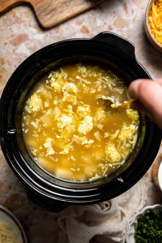 Creamy slow cooker loaded baked potato soup made with tender potatoes, cheddar cheese, sour cream, and topped with bacon. An easy comfort food recipe. | aheadofthyme.com