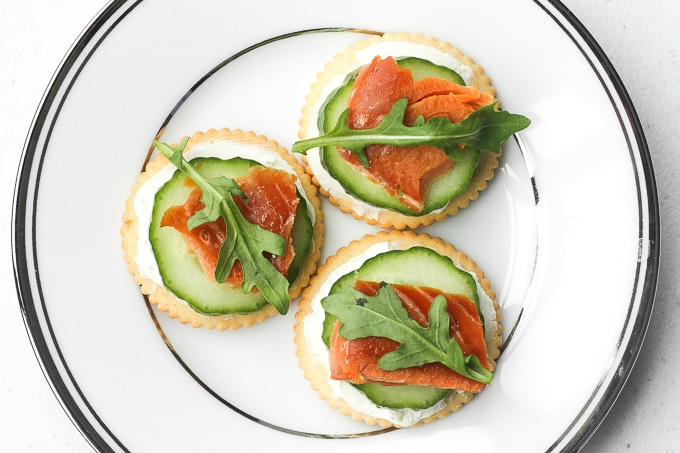 Smoked salmon and cream cheese cracker bites are topped with cucumber and arugula to make the perfect bite-size snacks. | aheadofthyme.com