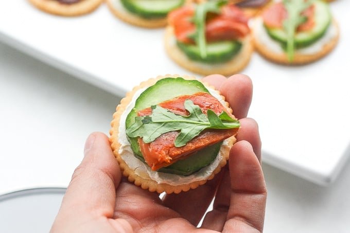 Smoked salmon and cream cheese cracker bites are topped with cucumber and arugula to make the perfect bite-size snacks. | aheadofthyme.com