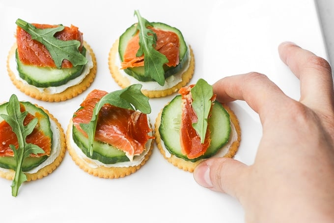 Smoked salmon and cream cheese cracker bites are topped with cucumber and arugula to make the perfect bite-size snacks. | aheadofthyme.com