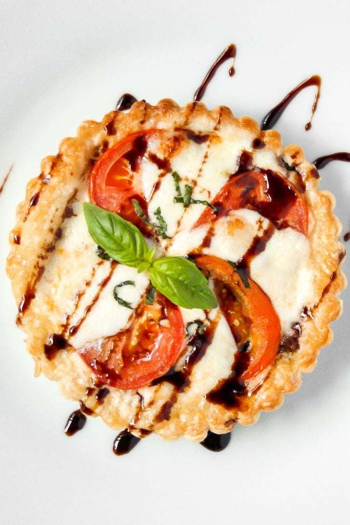 Looking for the perfect appetizer or light lunch? Try a tomato and mozzarella tart topped with basil and a drizzle of pomegranate molasses! | aheadofthyme.com