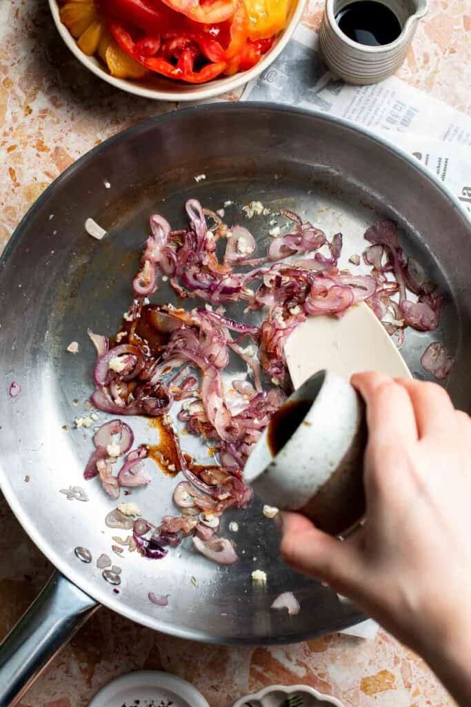 Adding balsamic vinegar to the caramelized onion mixture.