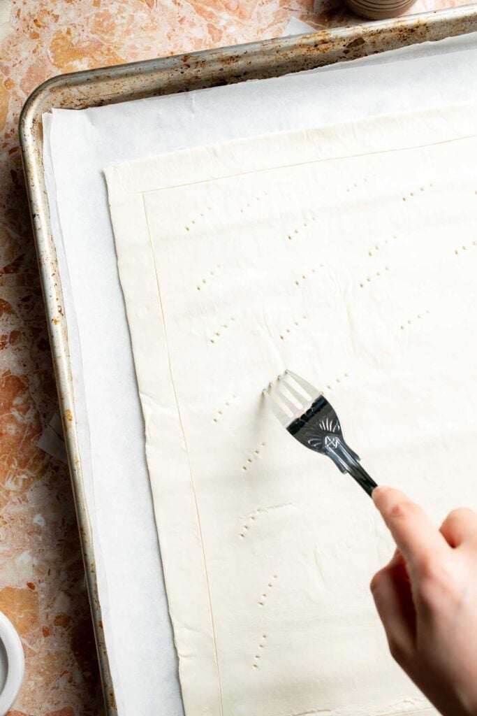 Pricking the center of the puff pastry with a fork.