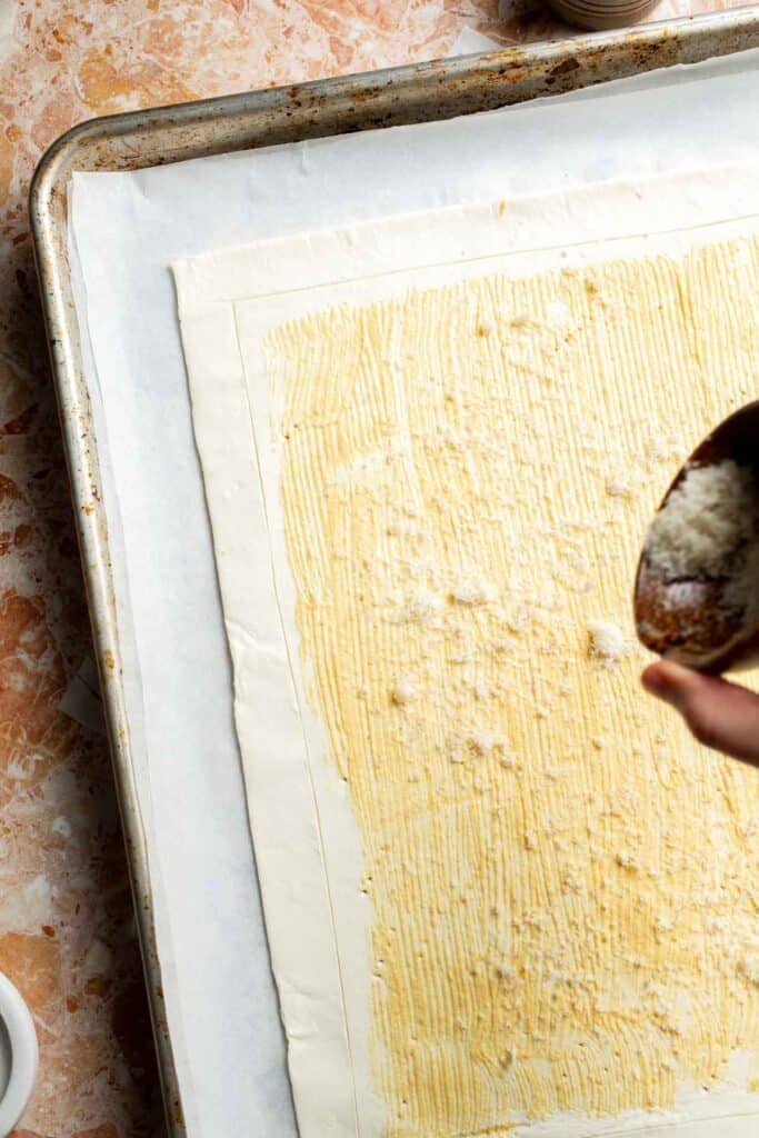 Sprinkling grated Parmesan cheese over the Dijon mustard.