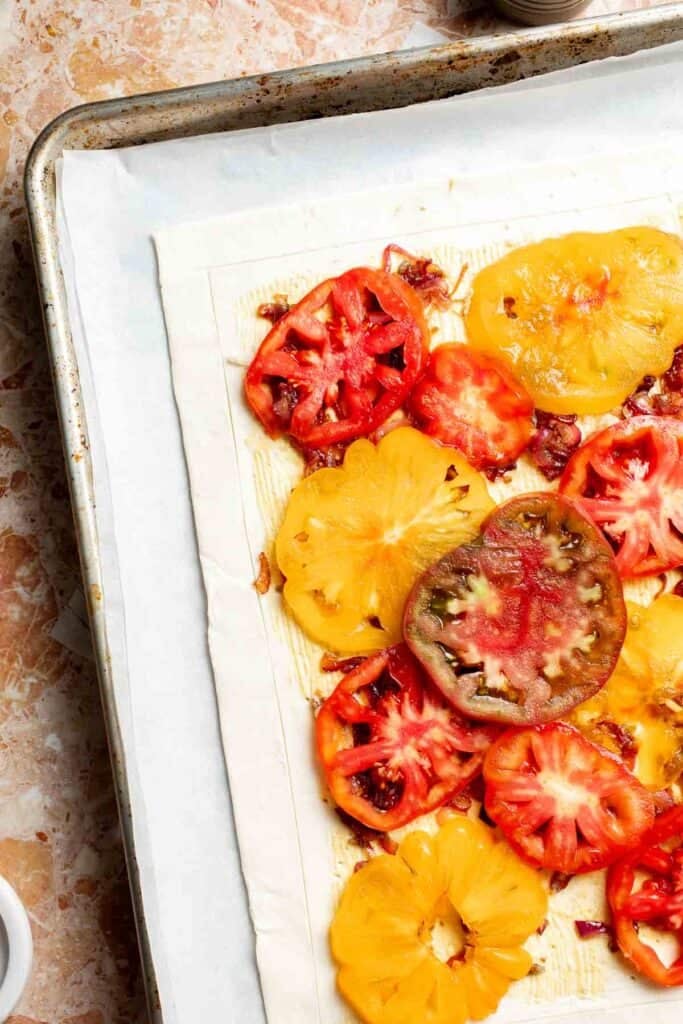 Arranging sliced tomatoes over the puff pastry tart.