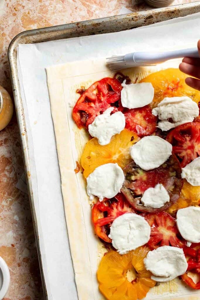 Brushing the border of the tomato mozzarella tart with egg wash.