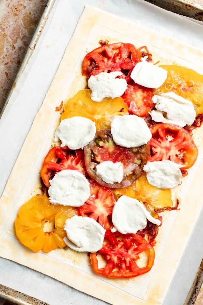 Tomato and mozzarella slices arranged over caramelized onions on puff pastry.
