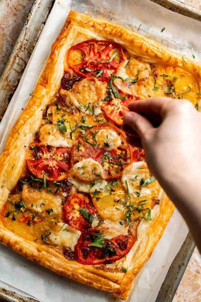 Adding flaked salt to the baked Tomato Puff Pastry Tart.