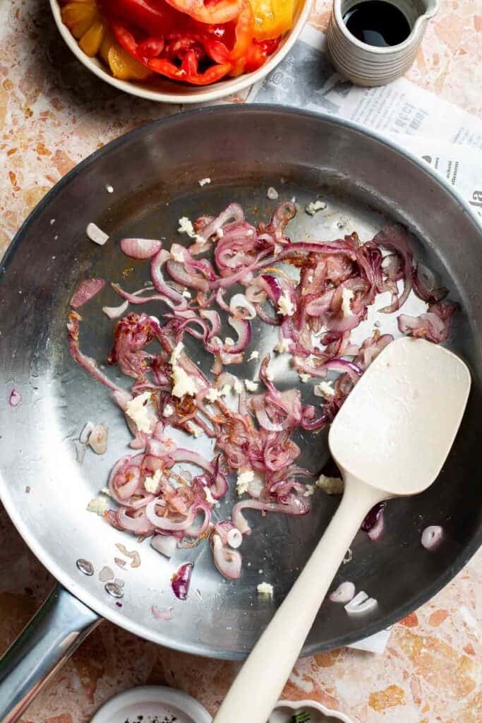 Adding minced garlic to the lightly caramelized onions.