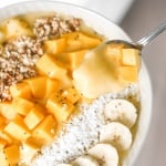 Mango pineapple tropical smoothie bowl? Yes, please! Who doesn't love pineapples and mangos blended together and topped with more fruit, granola, and coconut? | aheadofthyme.com