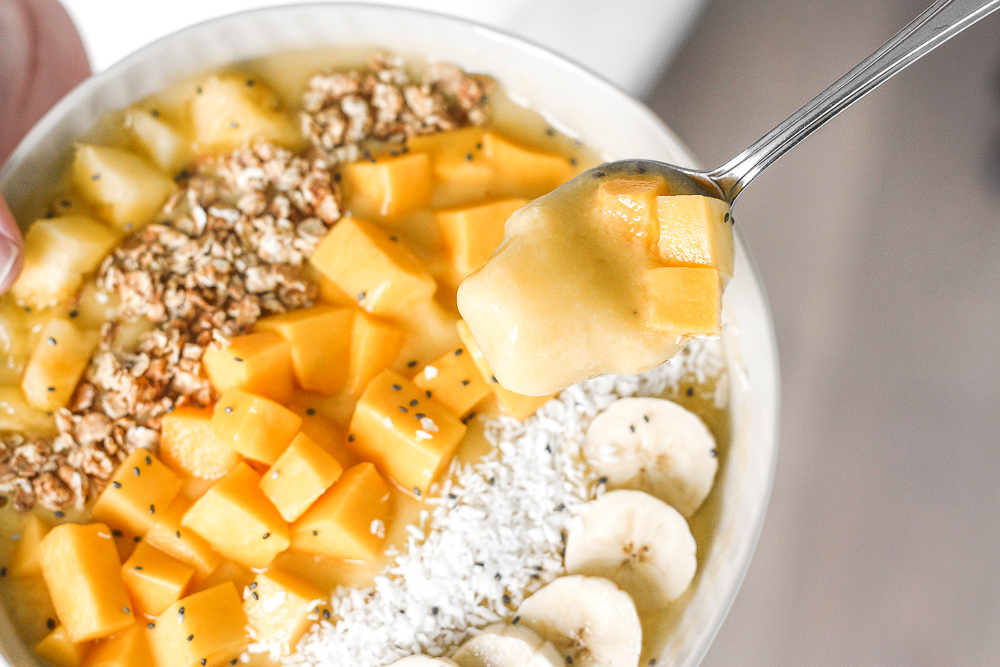 Mango pineapple tropical smoothie bowl? Yes, please! Who doesn't love pineapples and mangos blended together and topped with more fruit, granola, and coconut? | aheadofthyme.com