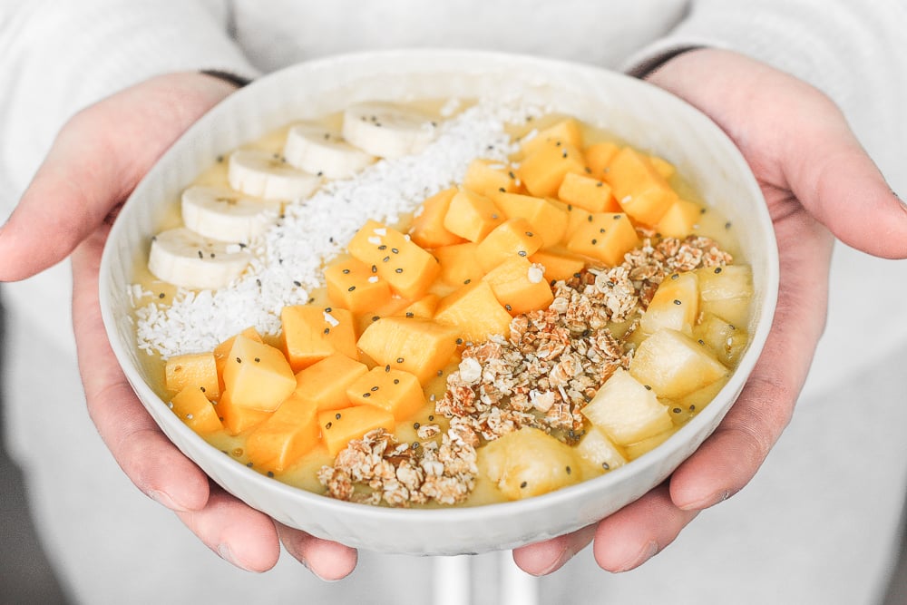 Mango pineapple tropical smoothie bowl? Yes, please! Who doesn't love pineapples and mangos blended together and topped with more fruit, granola, and coconut? | aheadofthyme.com