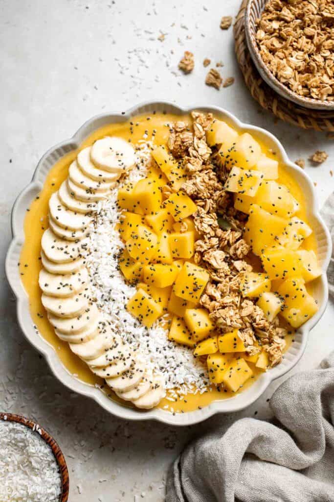 Mango Pineapple Tropical Smoothie Bowl is the perfect summer bowl, packed with pineapples and mangos and topped with more fruit, granola, and coconut. | aheadofthyme.com
