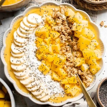 Mango Pineapple Tropical Smoothie Bowl is the perfect summer bowl, packed with pineapples and mangos and topped with more fruit, granola, and coconut. | aheadofthyme.com