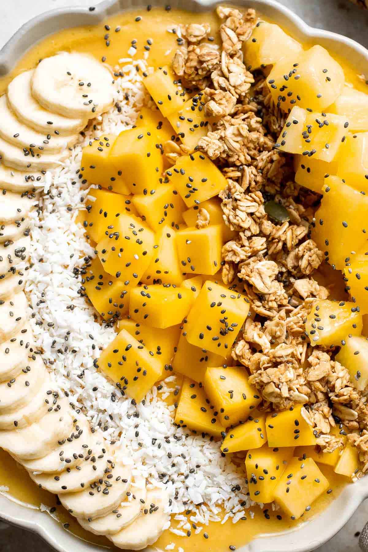Mango Pineapple Tropical Smoothie Bowl is the perfect summer bowl, packed with pineapples and mangos and topped with more fruit, granola, and coconut. | aheadofthyme.com