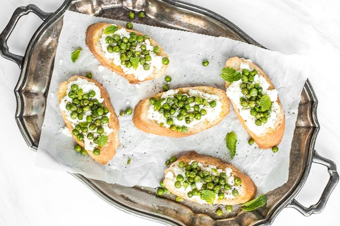 Get ready for spring with this impressive appetizer, crostini with ricotta, peas and mint! The way creamy ricotta pairs with fresh English peas and mint is unparalleled! Trust me, SO delicious. | aheadofthyme.com