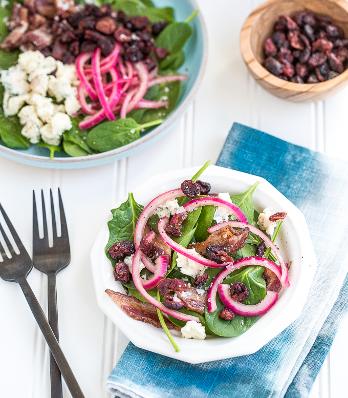 Every bite of pickled red onion and blue cheese spinach salad is the perfect bite! The bold flavors of blue cheese, maple bacon, and dried cranberries compliment the pickled red onions, creating the perfectly balanced dish — salty, sweet, acidic. | aheadofthyme.com