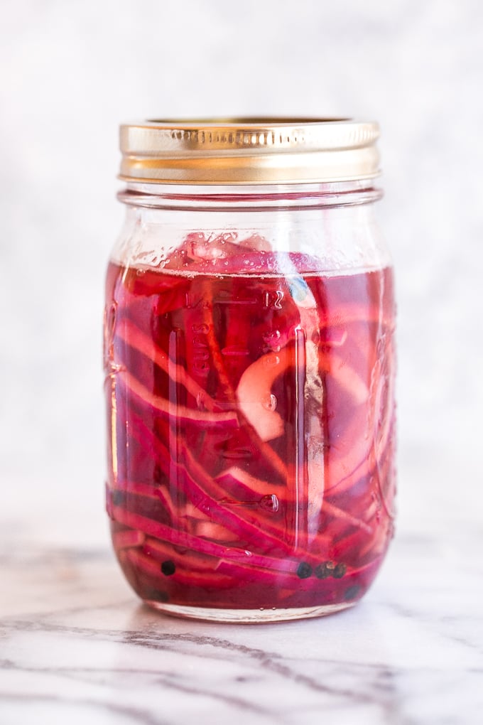 These quick and easy pickled red onions are going to change your life. They are incredibly versatile and add amazing acidity to otherwise simple dishes. I put them on everything from tacos to scrambled eggs to salads and sandwiches. | aheadofthyme.com