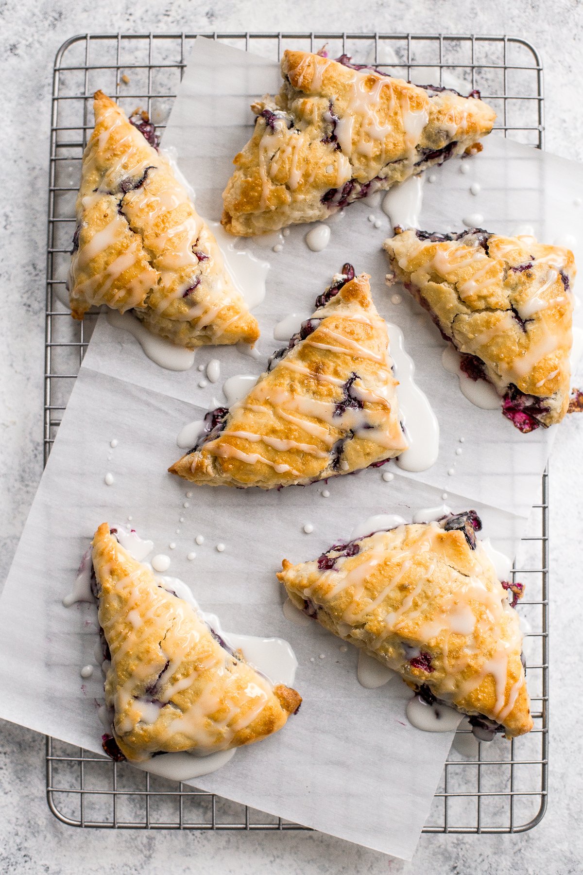 Glazed lemon blueberry scones are total breakfast goals! Blueberries and lemon partner together in a light, tender and flakey scone, drizzled with a sweet lemon glaze that is nothing short of impressive. | aheadofthyme.com