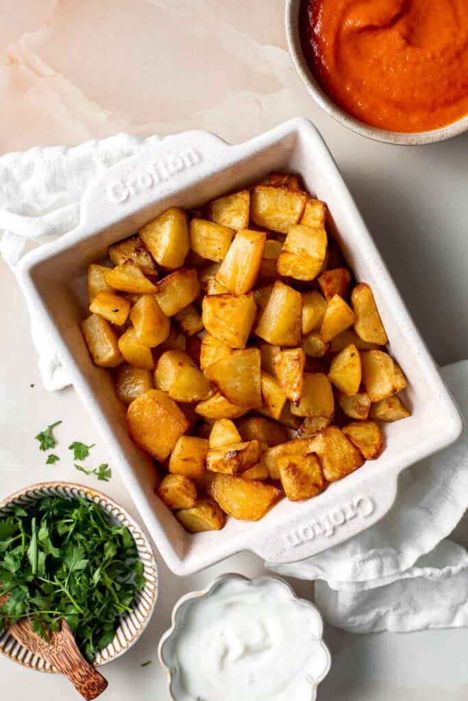 Skip the tapas bar and make Patatas Bravas at home with crispy, roasted potatoes smothered in a homemade sweet and spicy tomato sauce and garlic aioli. | aheadofthyme.com