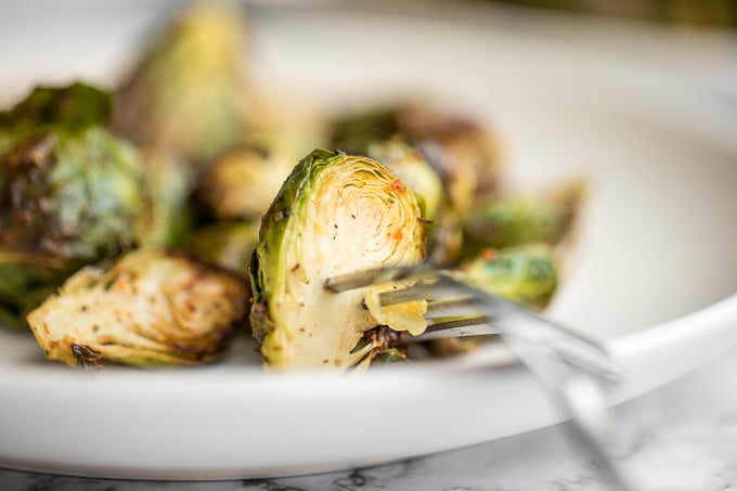 Tender and crispy roasted air fryer brussels sprouts cooks in less than 12 minutes with very little oil. It is a holiday table game changer. | aheadofthyme.com