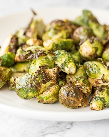 Tender and crispy roasted air fryer brussels sprouts cooks in less than 12 minutes with very little oil. It is a holiday table game changer. | aheadofthyme.com