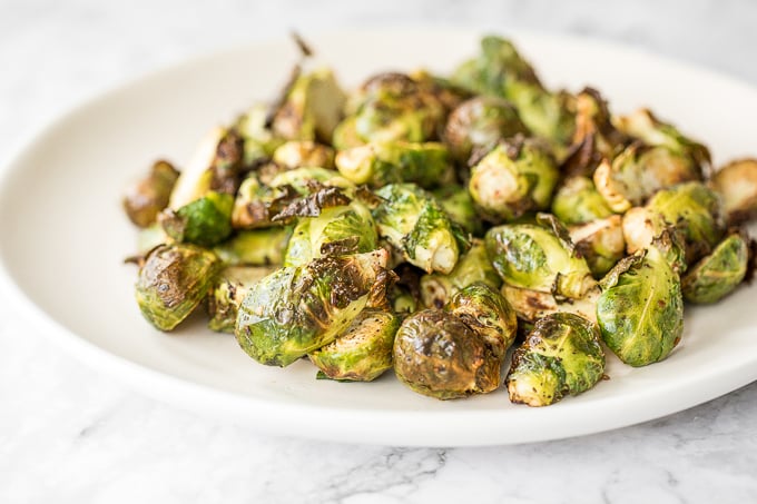 Tender and crispy roasted air fryer brussels sprouts cooks in less than 12 minutes with very little oil. It is a holiday table game changer. | aheadofthyme.com