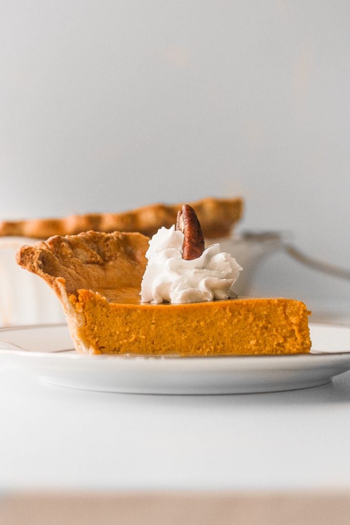 Thanksgiving just isn't the same without a slice of classic Thanksgiving pumpkin pie with flaky crust, smooth pumpkin filling, and topped with whipped cream and pecans. | aheadofthyme.com