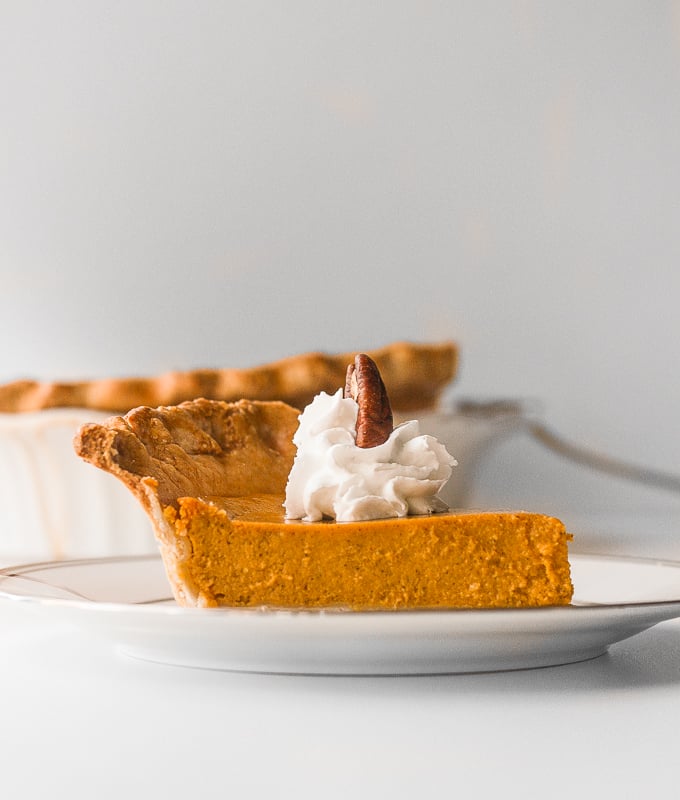 Thanksgiving just isn't the same without a slice of classic Thanksgiving pumpkin pie with flaky crust, smooth pumpkin filling, and topped with whipped cream and pecans. | aheadofthyme.com