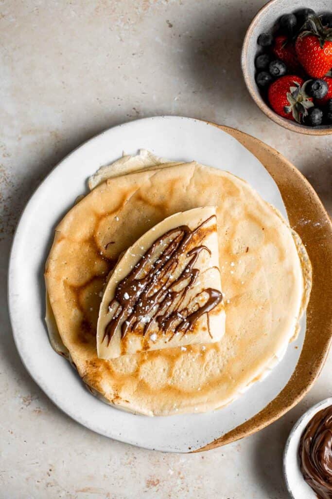 Nutella crepes with berries are sweet and indulgent. These French pancakes are an easy to make blender recipe that will have you craving breakfast all day. | aheadofthyme.com