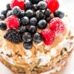 This healthy banana smash cake is held together with a whipped coconut cream frosting and topped with more cream, mixed berries and a drizzle of maple syrup. | aheadofthyme.com