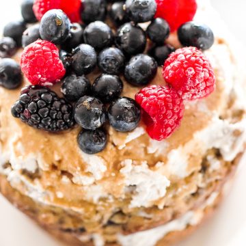 This healthy banana smash cake is held together with a whipped coconut cream frosting and topped with more cream, mixed berries and a drizzle of maple syrup. | aheadofthyme.com