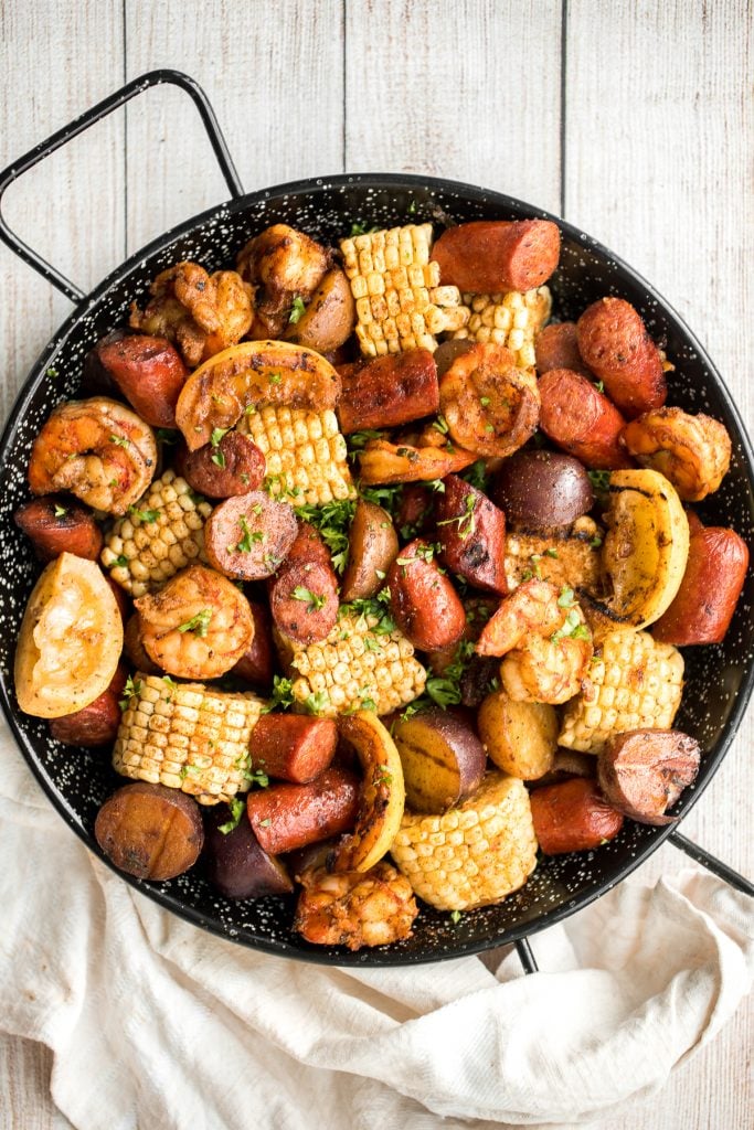 Easy, garlicky and buttery grilled shrimp boil with prawns, corn, baby potatoes and sausage, seasoned and tossed with parsley takes just 20 minutes to cook. | aheadofthyme.com