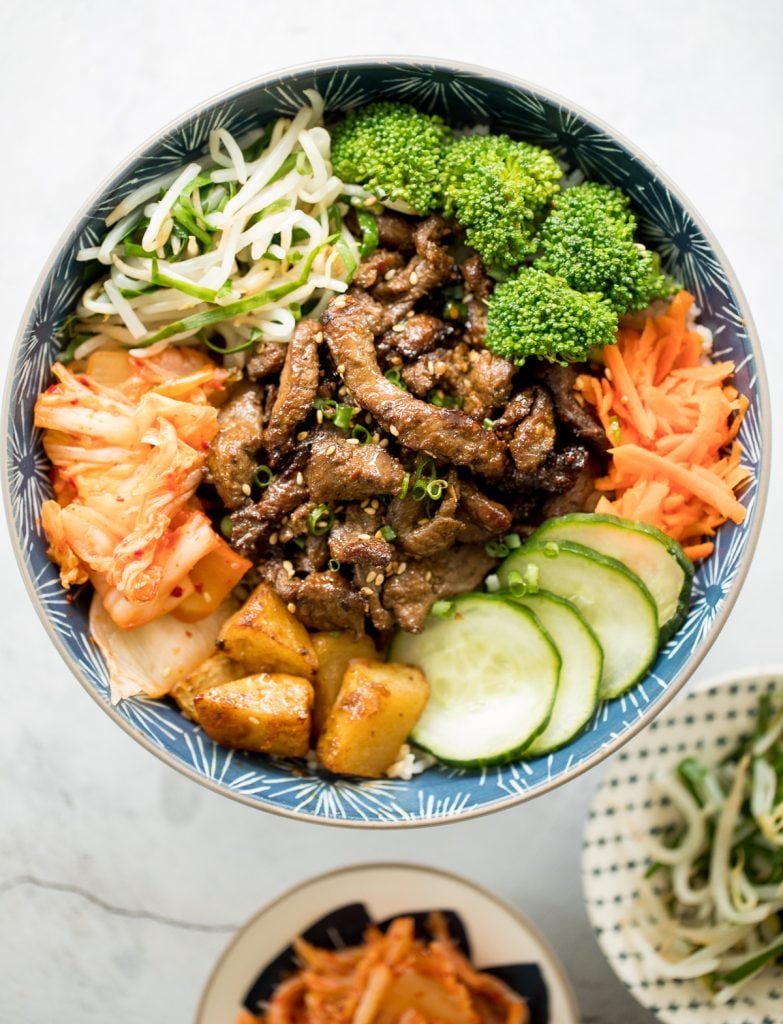 Korean beef steak rice bowl is loaded with tender and juicy strips of beef, marinated vegetable sides (banchan), and kimchi. Make it in under 30 minutes! | aheadofthyme.com