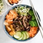 Korean beef steak rice bowl is loaded with tender and juicy strips of beef, marinated vegetable sides (banchan), and kimchi. Make it in under 30 minutes! | aheadofthyme.com