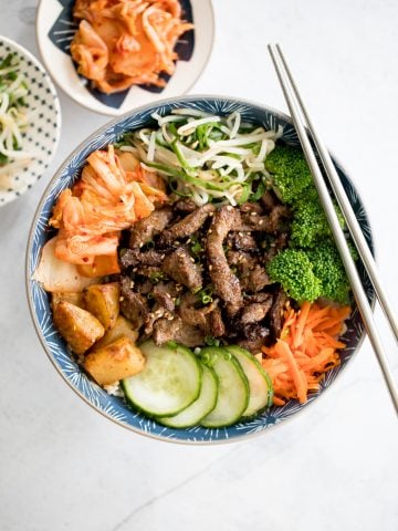 Korean beef steak rice bowl is loaded with tender and juicy strips of beef, marinated vegetable sides (banchan), and kimchi. Make it in under 30 minutes! | aheadofthyme.com