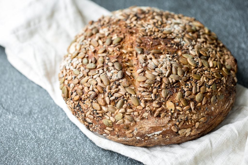 Small batch multi-seeded whole wheat sourdough bread is airy and chewy, is loaded with seeds inside, and has a signature crispy crust coated in more seeds. | aheadofthyme.com