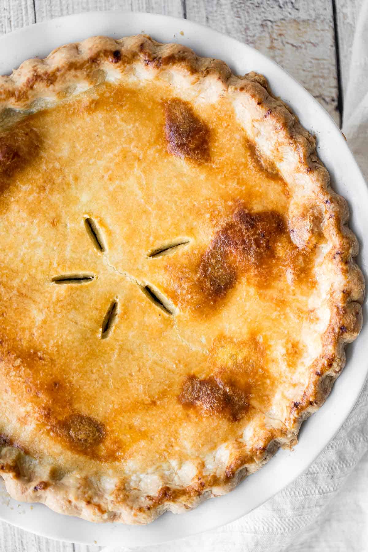 Overhead view of a whole baked ground beef meat pie with a golden brown, vented crust